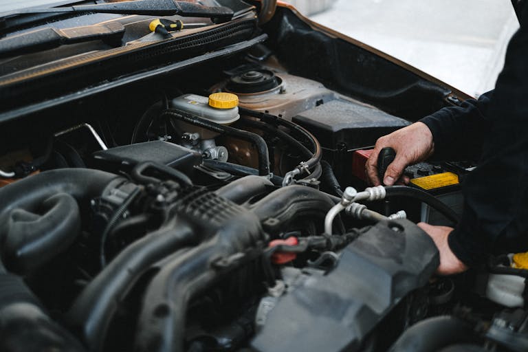 Close-up of a mechanic's hands working on a car engine, showcasing repair work.